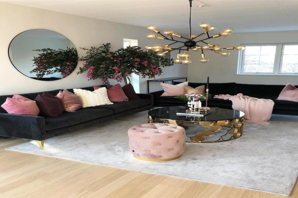 Black sofa with gold legs and dusty pink throw pillows, in front